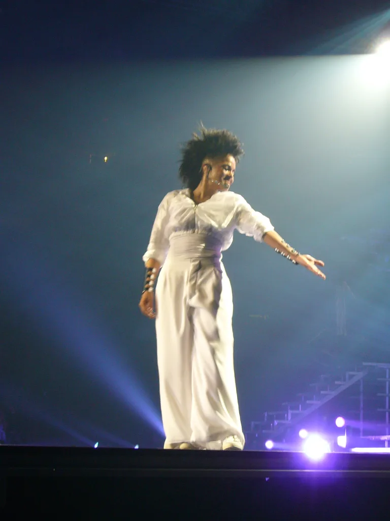 Janet Jackson dainuoja scenoje Vankuveryje, ištiesusi ranką į šoną.