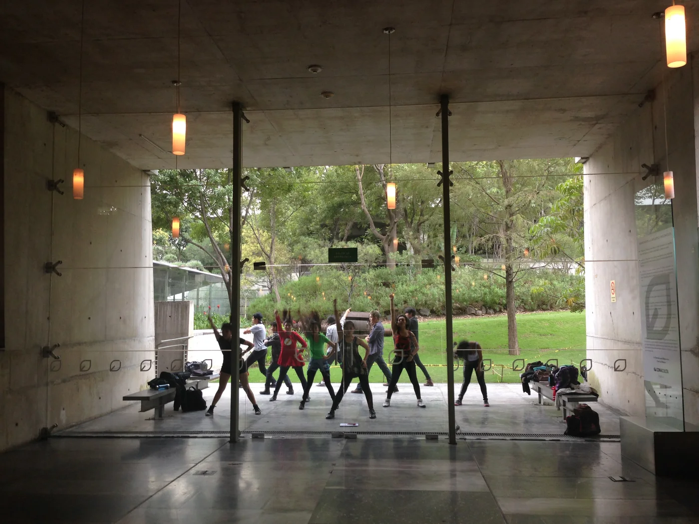 Grupė repetuoja K-pop choreografiją prie Biblioteca Vasconcelos stiklinių durų.