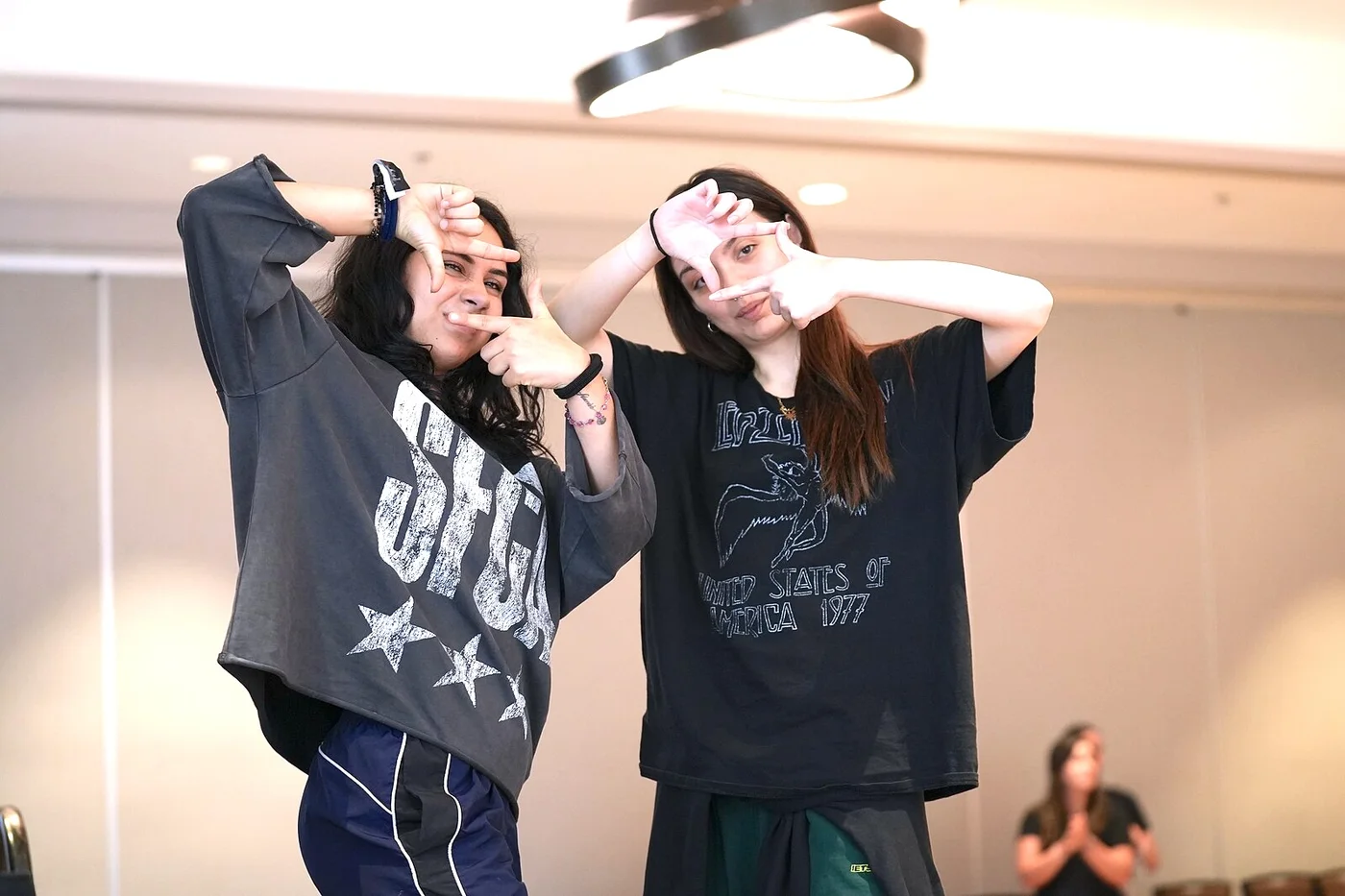 Du Fuego Dance Crew šokėjai pamokoje rankomis kuria rėmus aplink veidus.