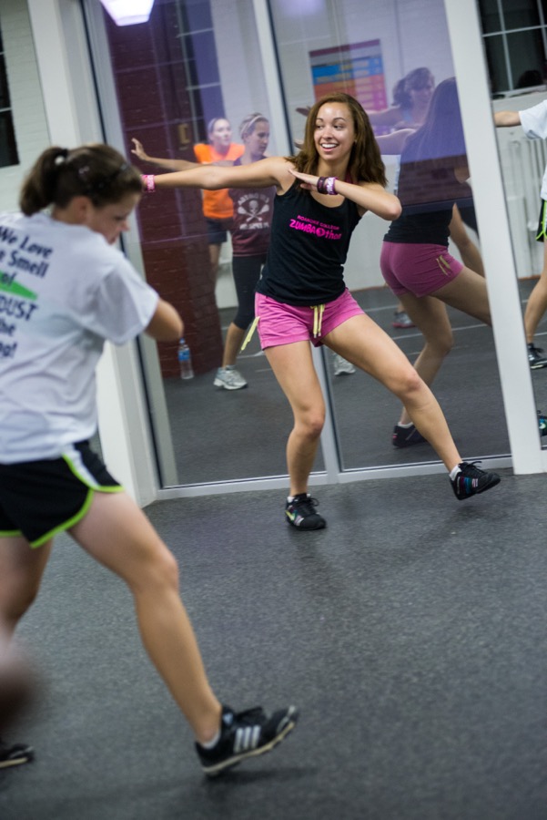 Zumba instruktorius rodo judesį dalyviams prie salės veidrodžio.